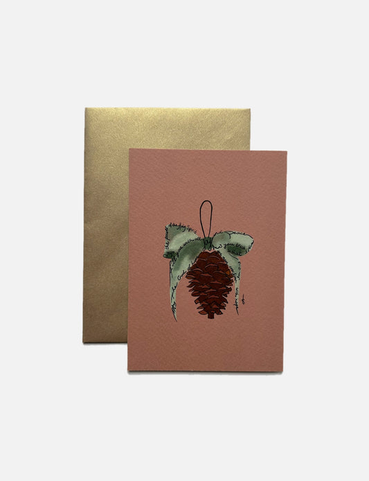 Handgemaakte A6 kerstkaart met illustratie van dennenappel met groene strik, bijbeltekst Romeinen 15:13, terracotta achtergrond, geprint op Tintoretto Gesso papier met metallic gouden envelop – christelijke kerstkaart.